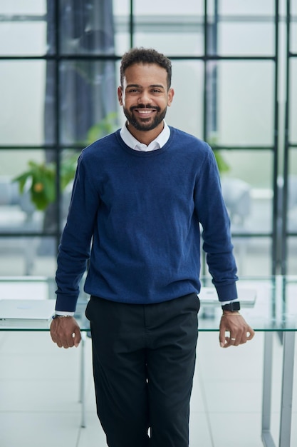 Cheerful young african man in full suit keeping arms crossed and looking at camera