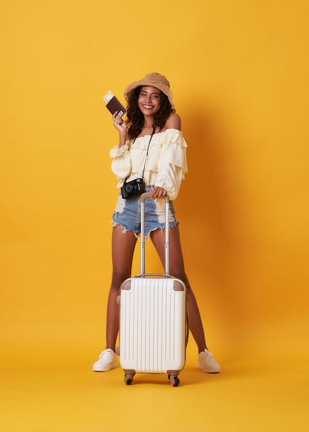 Cheerful young african woman dressed in summer clothes holding a passport with money