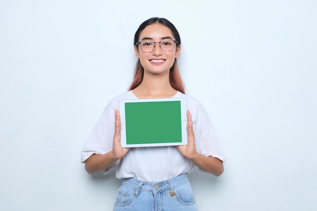 Cheerful young Asian girl in white tshirt showing digital tablet with empty screen isolated on white background