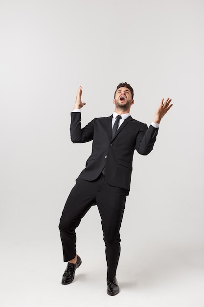 Cheerful young bearded business man show hand up excited with clenched fists.