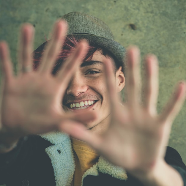 Cheerful young boy smiling and put hands in front of him to do stop gesture Hidden face and enjoyed expression for teenager hispanic male Age issue and lifestyle concept