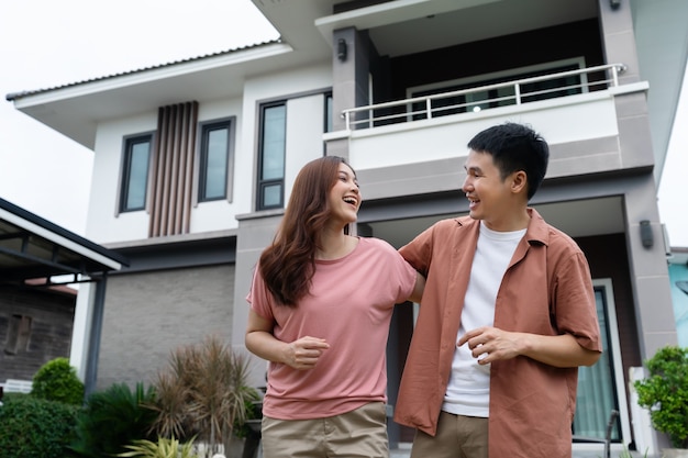 Cheerful young couple standing outside their house