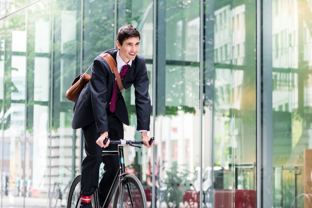 Cheerful young employee with a healthy lifestyle riding an utility bicycle to a modern workplace in Berlin