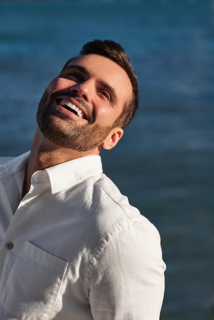 Cheerful young ethnic guy smiling near sea in sunlight