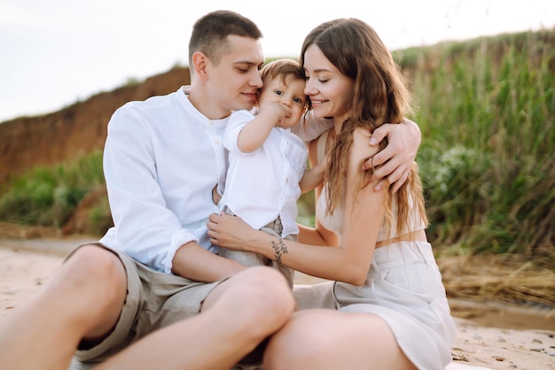 Cheerful young family with little baby boy spending time together on the beach