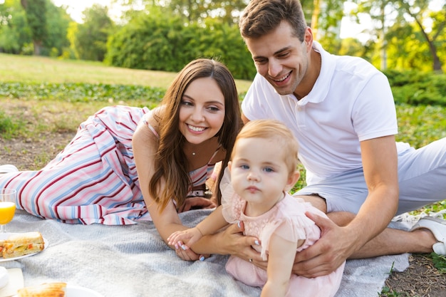 Cheerful young family with little baby girl spending time together