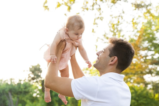 Cheerful young father playing with his little daughter