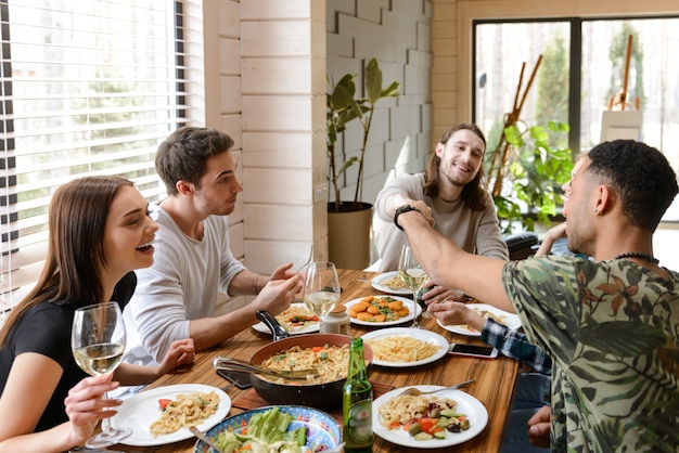 Cheerful young friends eating and having fun at the table