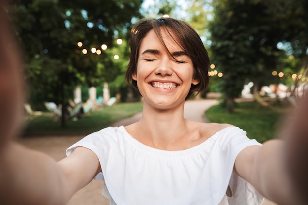 Cheerful young girl with eyes closeed taking a selfie