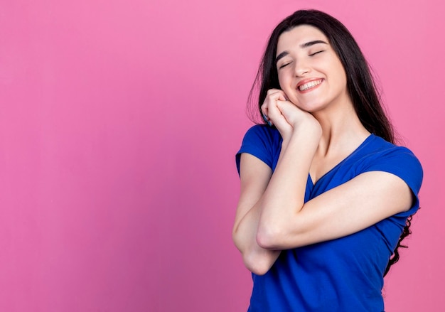 Cheerful young lady holding her hand together and smiling on pink background