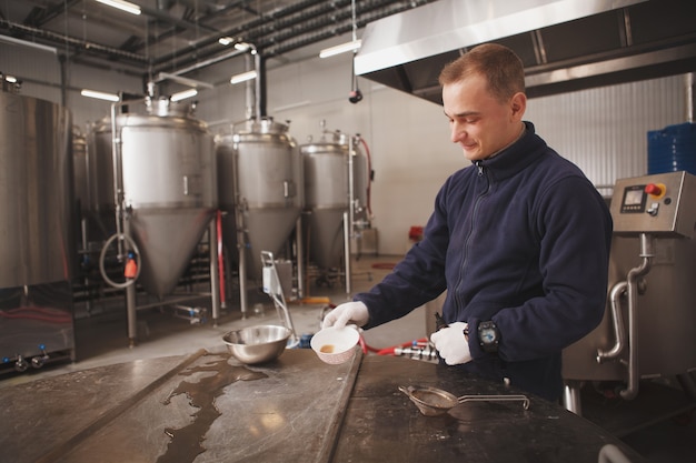 Cheerful young male brewer enjoying working at beer factory