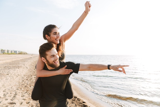 Cheerful young man carrying his girlfriend on his back