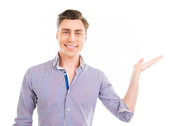 Cheerful young man gesturing with hand and showing product