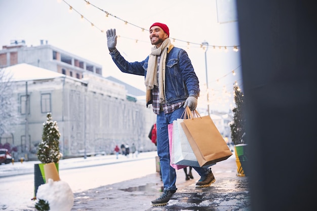 Cheerful young man greeting somebody in snowy street