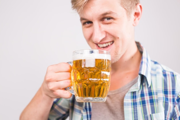 Photo cheerful young man holding a beer mug full of beer and smiling on white background close up portrait                      person