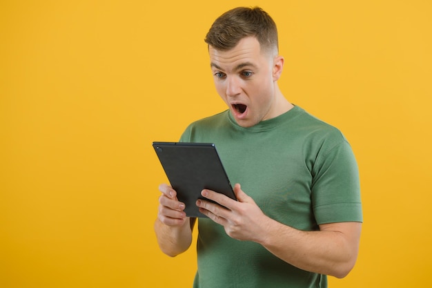 Cheerful young man using digital tablet on yellow background