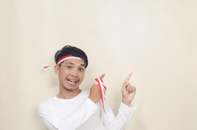 Cheerful young man wearing white tshirt smiling pointing to empty space Independence concept