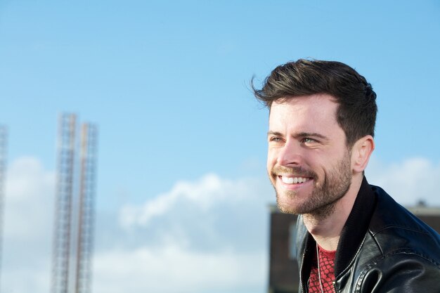 Cheerful young man with beard smiling outdoors