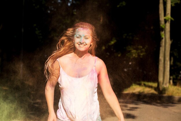 Cheerful young model with hair in motion playing with Holi dry paint