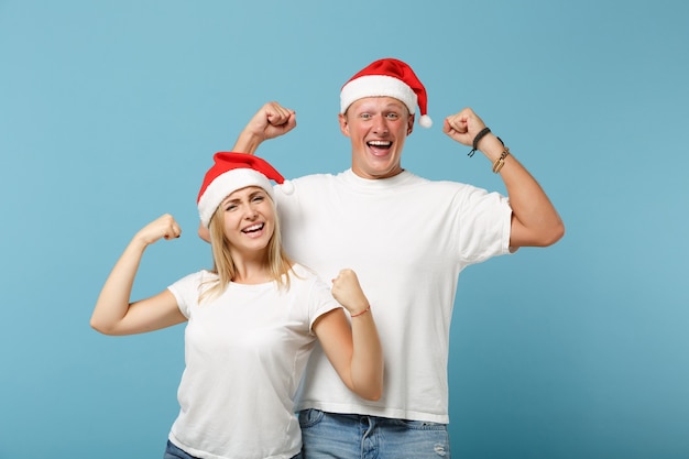 Cheerful young Santa couple friends guy and woman in Christmas hat posing 