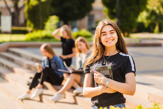 Cheerful young teen girl with book near friends