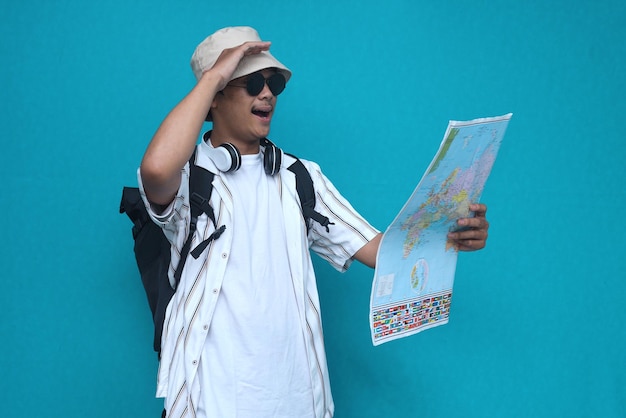 Cheerful young traveler tourist man in summer casual clothes hat holding map. Passenger traveling ab