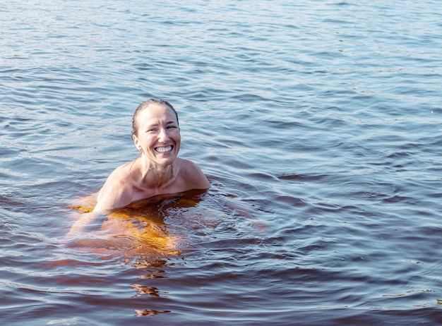 Cheerful young woman bathing in the lake