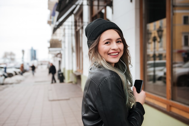 Cheerful young woman listening music with earphones.