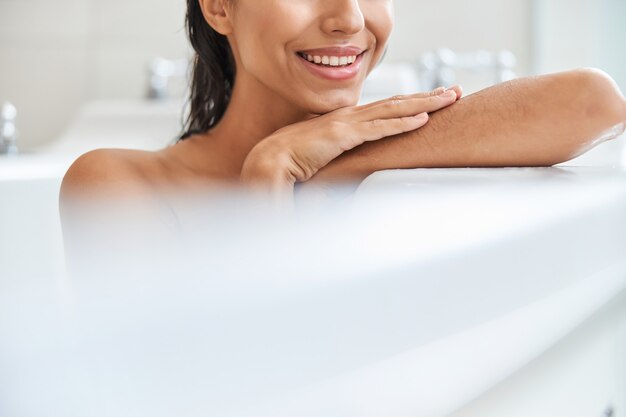 Cheerful young woman taking bath at home