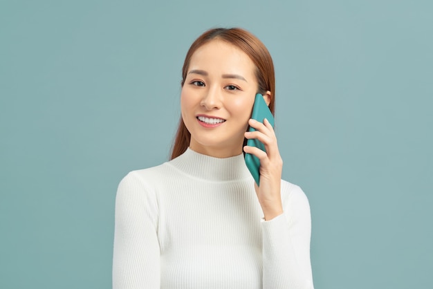 Cheerful young woman talking on mobile phone isolated on violet wall