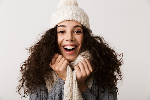 Cheerful young woman wearing winter scarf standing isolated over white wall