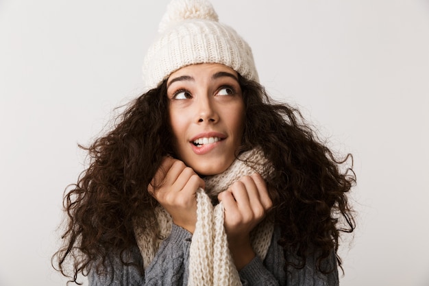 Cheerful young woman wearing winter scarf standing isolated over white wall