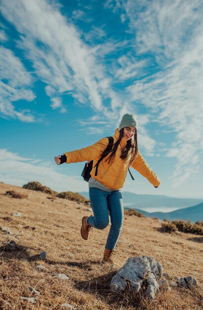 Cheering woman backpacker enjoy the view on sunrise mountain top cliff edge