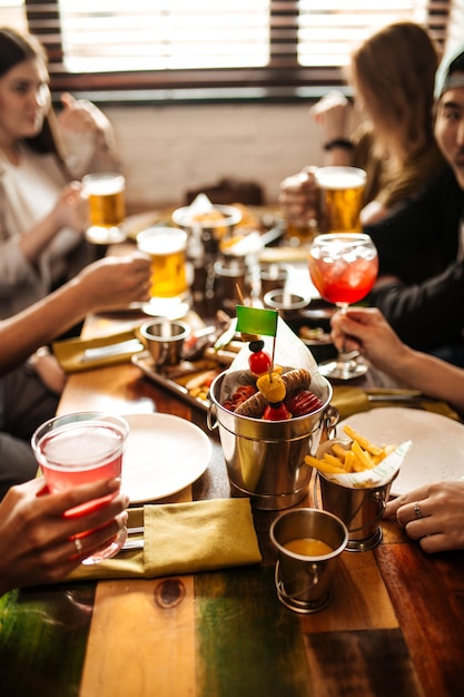 Cheers hand holding mugs with beer above the table