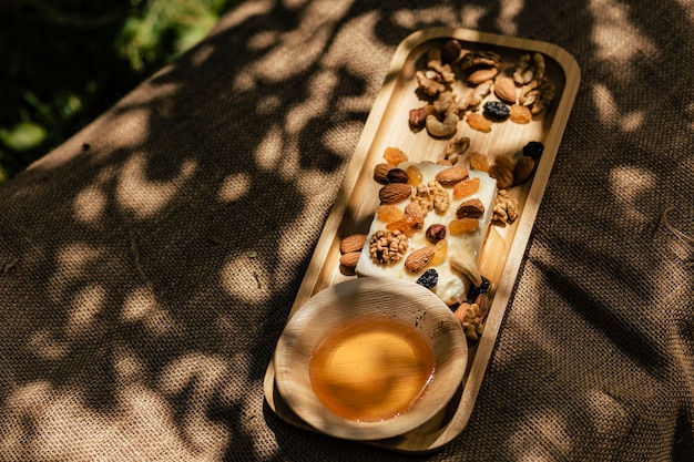 Cheese assortment with honey and nuts on natural burlap fabric in the garden