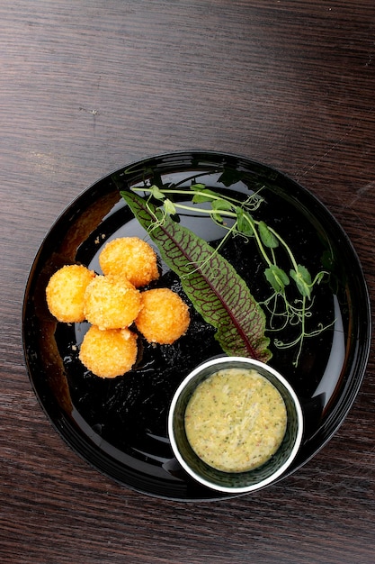 Cheese balls with honey mustard sauce On a glossy black plate