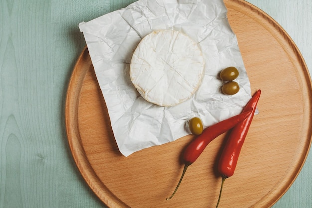 cheese brie camembert green olives chili on a wooden light background vintage photo processing