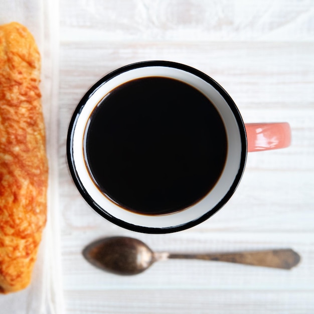 Cheese buns, bread with cheese and a cup of coffee with a spoon on a white wooden background