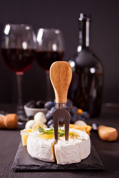 Cheese camembert brie on the board, two glasses and bottle of red wine