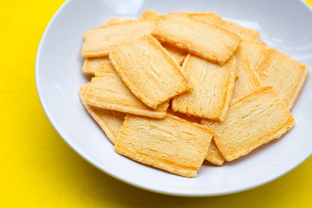 Cheese crispies in plate on yellow background