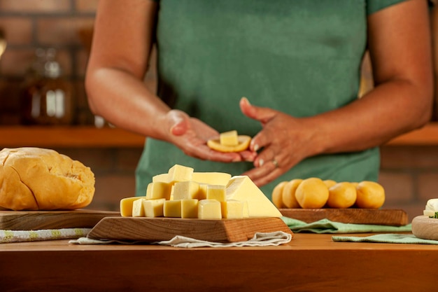 Cheese cubes with woman preparing brazilian croquettes stuffed with cheese in background