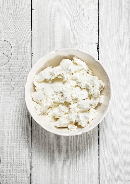 Cheese from fresh milk. On a white wooden surface.