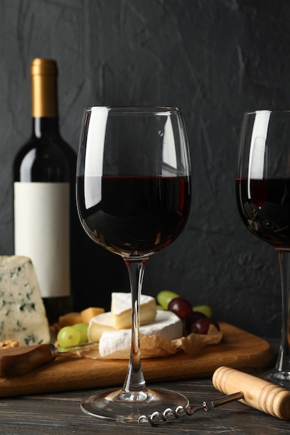 Cheese, grape, bottle and glasses with wine on wooden