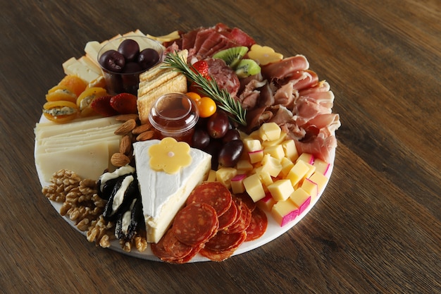 Cheese, ham, and sausage with olives on wooden background