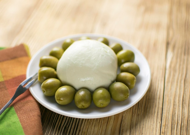 Cheese mozzarella and olives on a plate on a wooden background