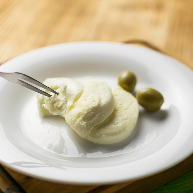 Cheese mozzarella and olives on a plate on a wooden background