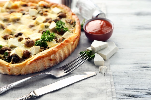 Cheese pie with mushrooms herbs and sour creme on wooden table background