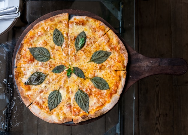 Cheese pizza with basil leaf fusion thai style top view on the wooden table.