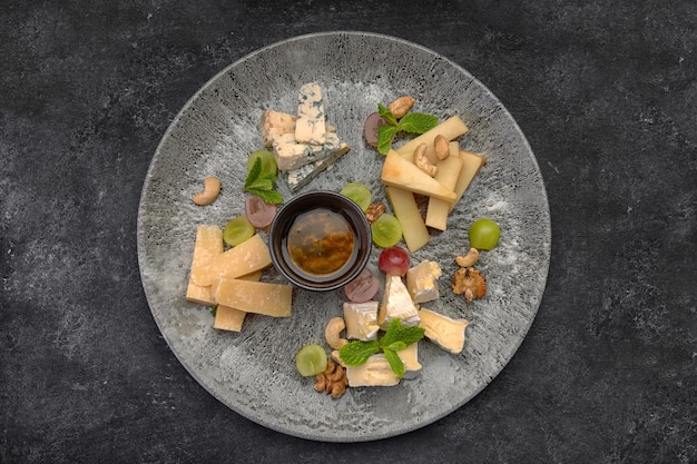 Cheese plate, assorted cheeses with mint, candied fruit, honey and cookies, on a  plate