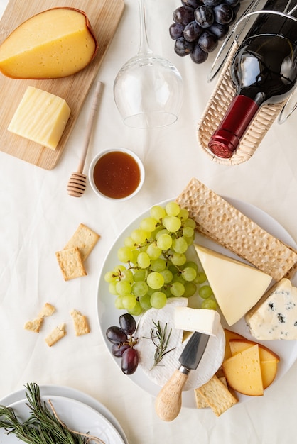 Cheese plate assortment served with honey, grapes, bread, wine and rosemary